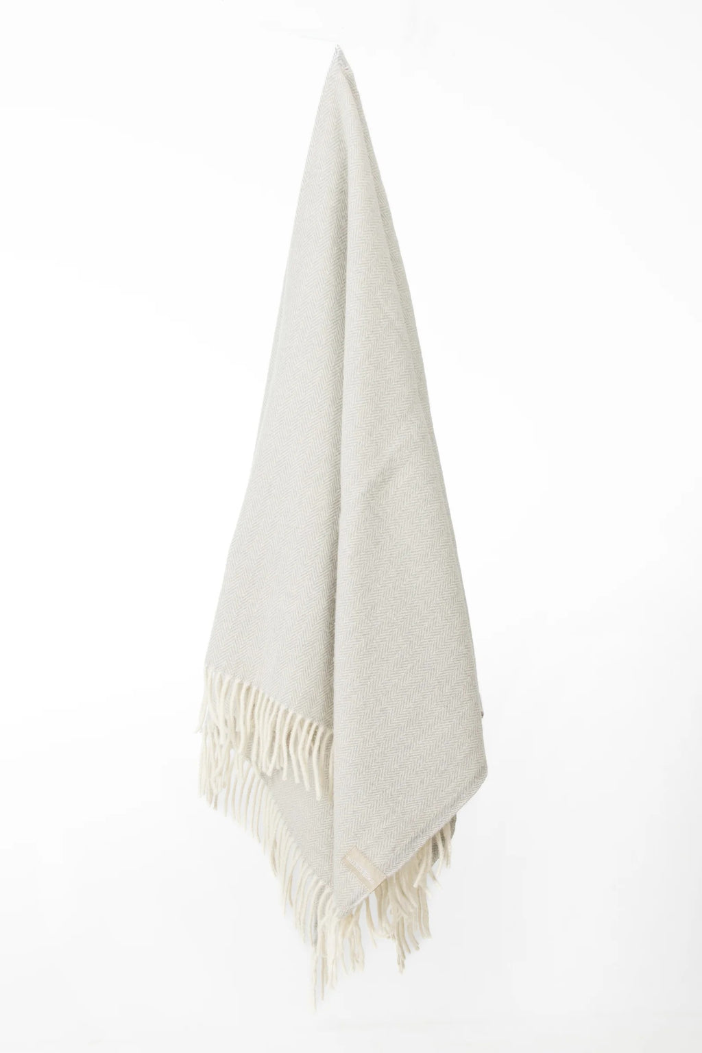 Palliser Ridge Herringbone throw in Dove Grey hanging in full drape, showing the fringed edge