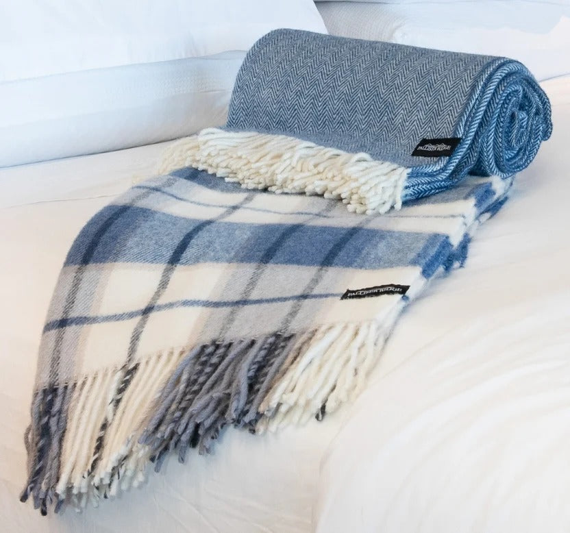 Palliser Ridge Twill Check throw in Royal Blue rolled to show the twill weave, styled on a bed