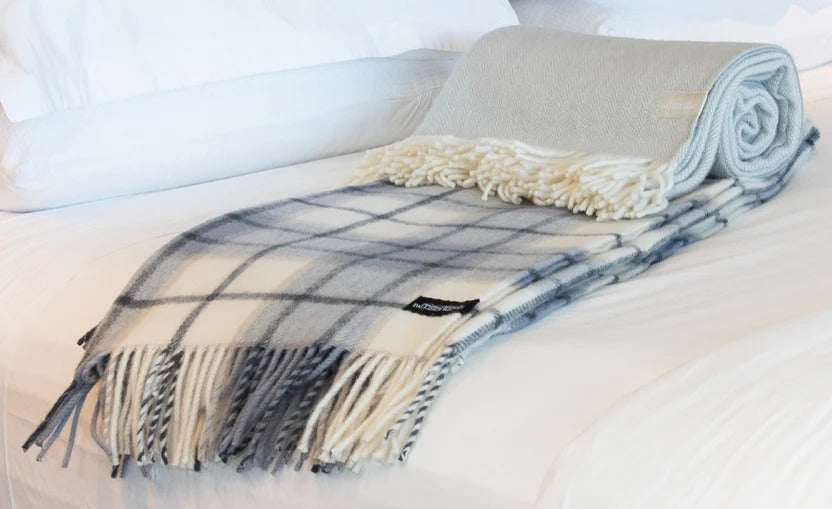 Palliser Ridge Twill Check lambswool throw in Dove Grey, rolled on a bed showing the fringe and plain reverse side