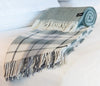 Palliser Ridge Twill Check lambswool throw in Forest, rolled on a bed showing the check pattern and plain reverse side