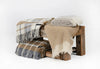 Palliser Ridge Twill Check lambswool throw in Mustard, folded and draped on a wooden bench with another folded throw alongside