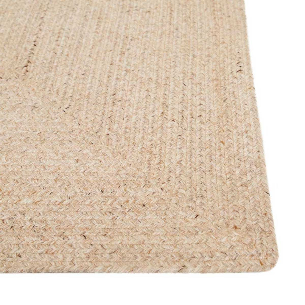 A corner view of a braided rug by Globe West and Soren Liv NZ in natural beige tones, perfect for outdoors or transition spaces. 