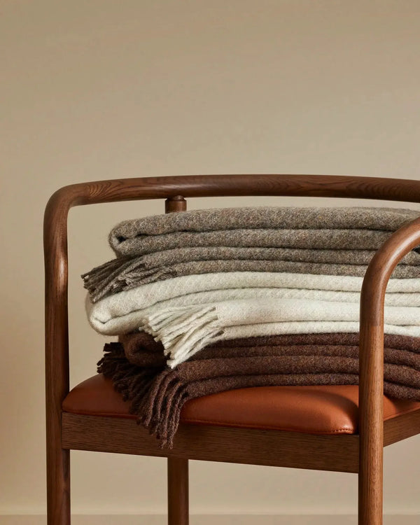 Stack of recycled wool throw blankets on a chair, by Weave Home nz