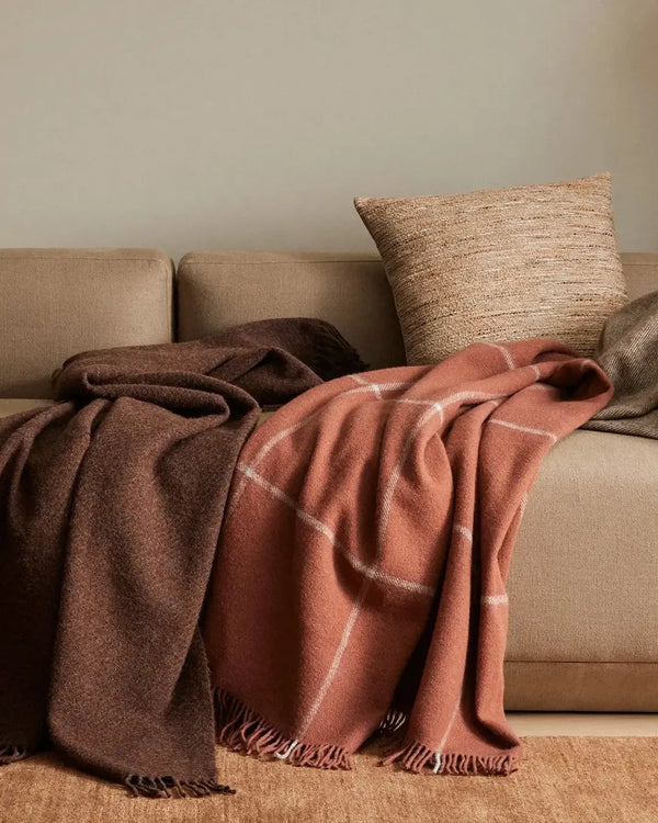 Two wool throw blankets on a couch in a stylish living room