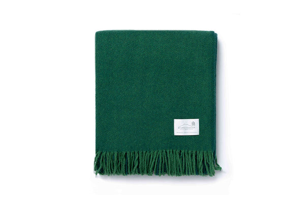 A folded green throw blanket by Ruanui Station NZ.