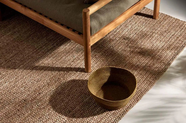 The brown Harbour Knot Outdoor rug by Globe West/ Soren Liv seen under a couch 