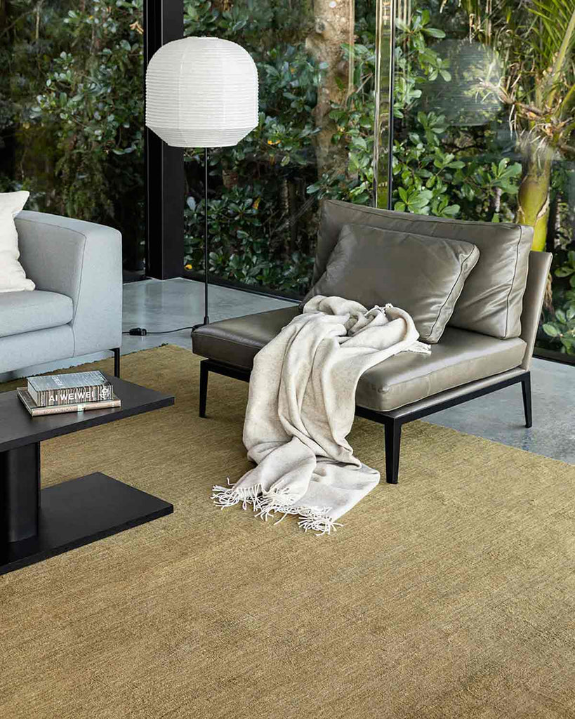 A chic modern lounge with leather chairs and a light green-yellow floor rug. 