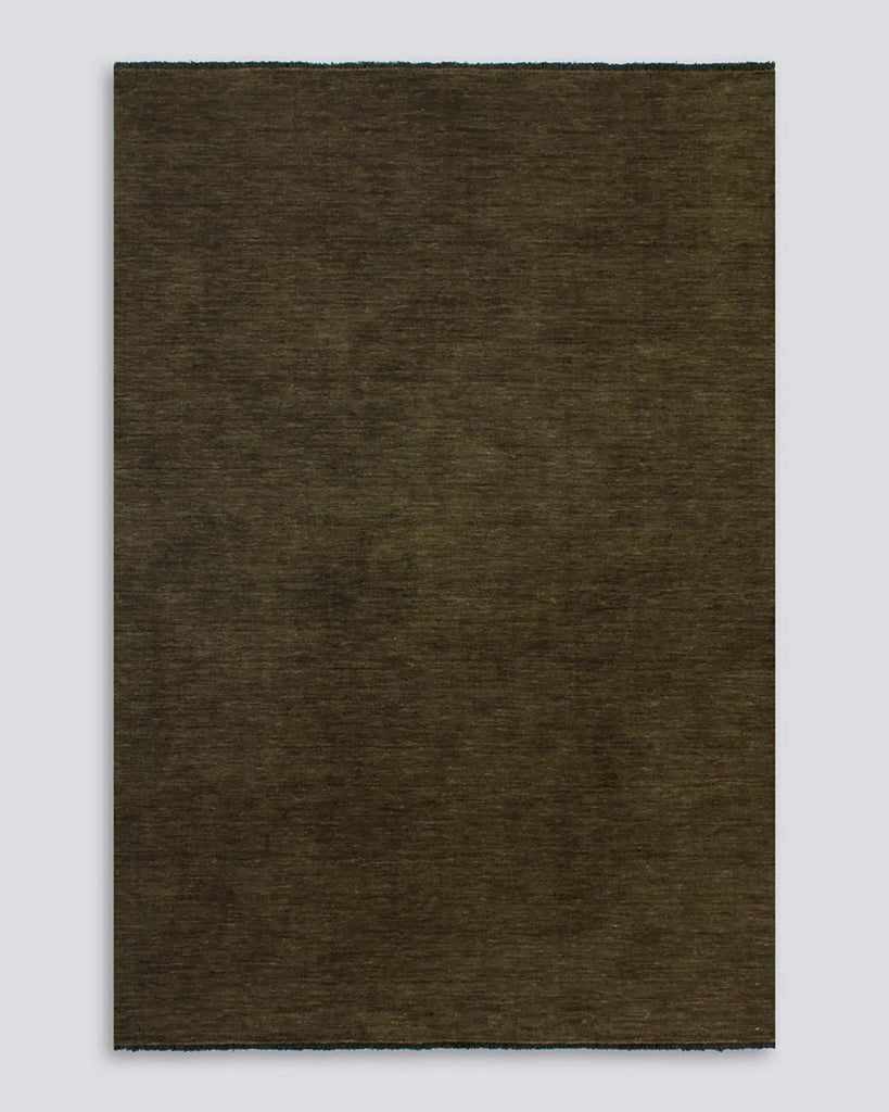 A full image of the Baya Sandringham floor rug in Moss, a deep, warm, green shade, made with fringed edges in 100% wool. 