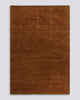 A full image of a warm red-brown floor rug with fringed edges in 100% wool. 