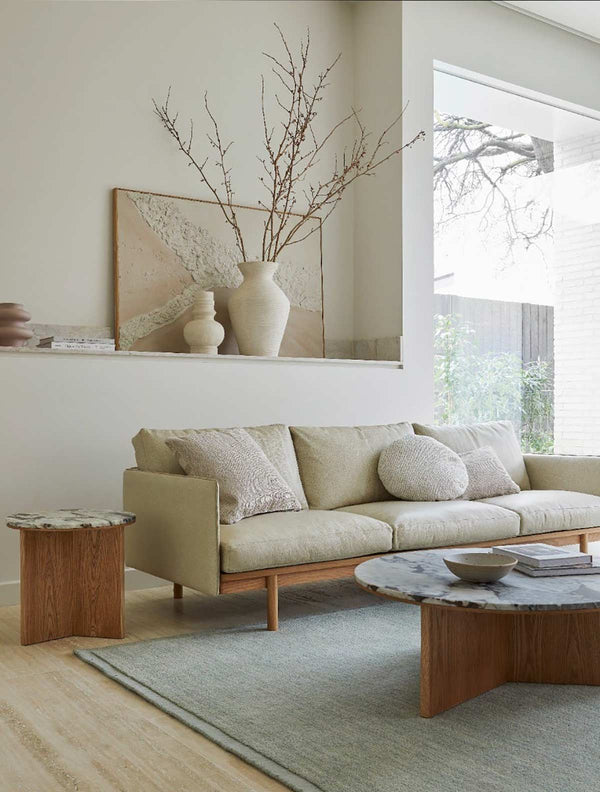 A handmade, 100% wool floor rug by Soren Liv NZ and Globe West, in subtle shades of light blue and green, shades of seafoam. The rug is situated in a stylish living room.  It has an indented border, giving interest and sophistication to the rug. 