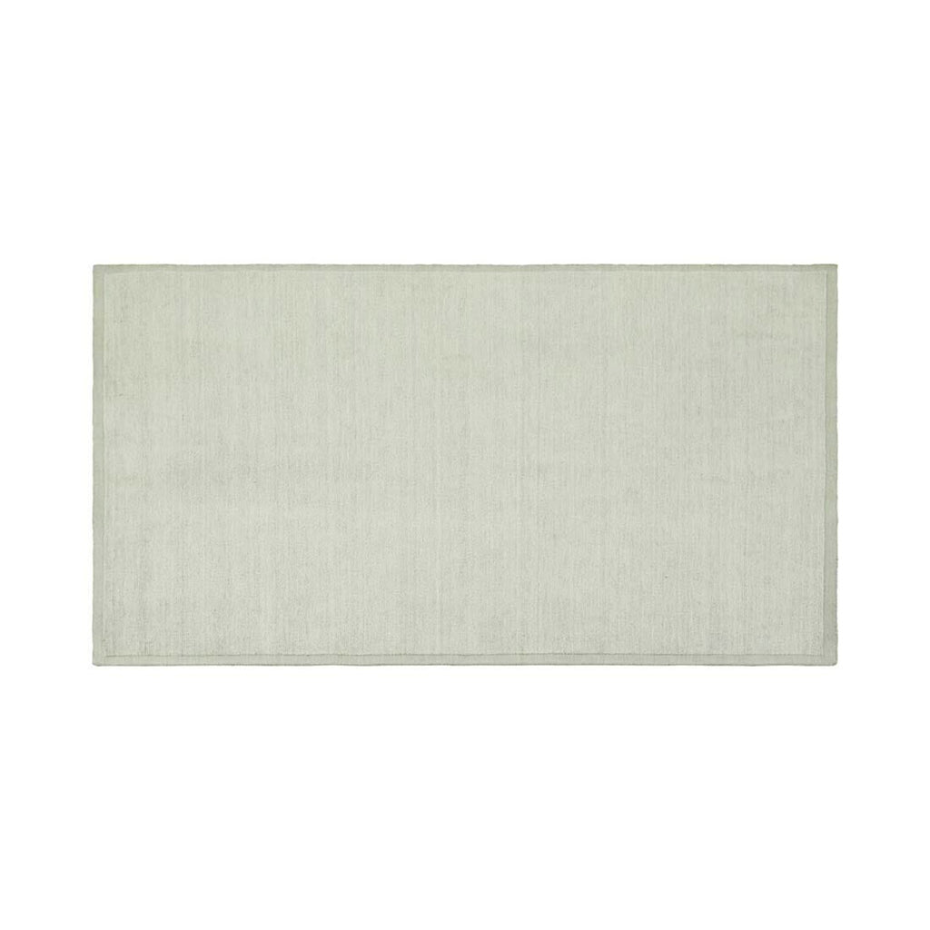 Full view of a handmade, 100% wool floor rug by Soren Liv NZ and Globe West, in subtle shades of light blue and green, shades of seafoam. The edges of the rug are indented, lending subtle sophistication.
