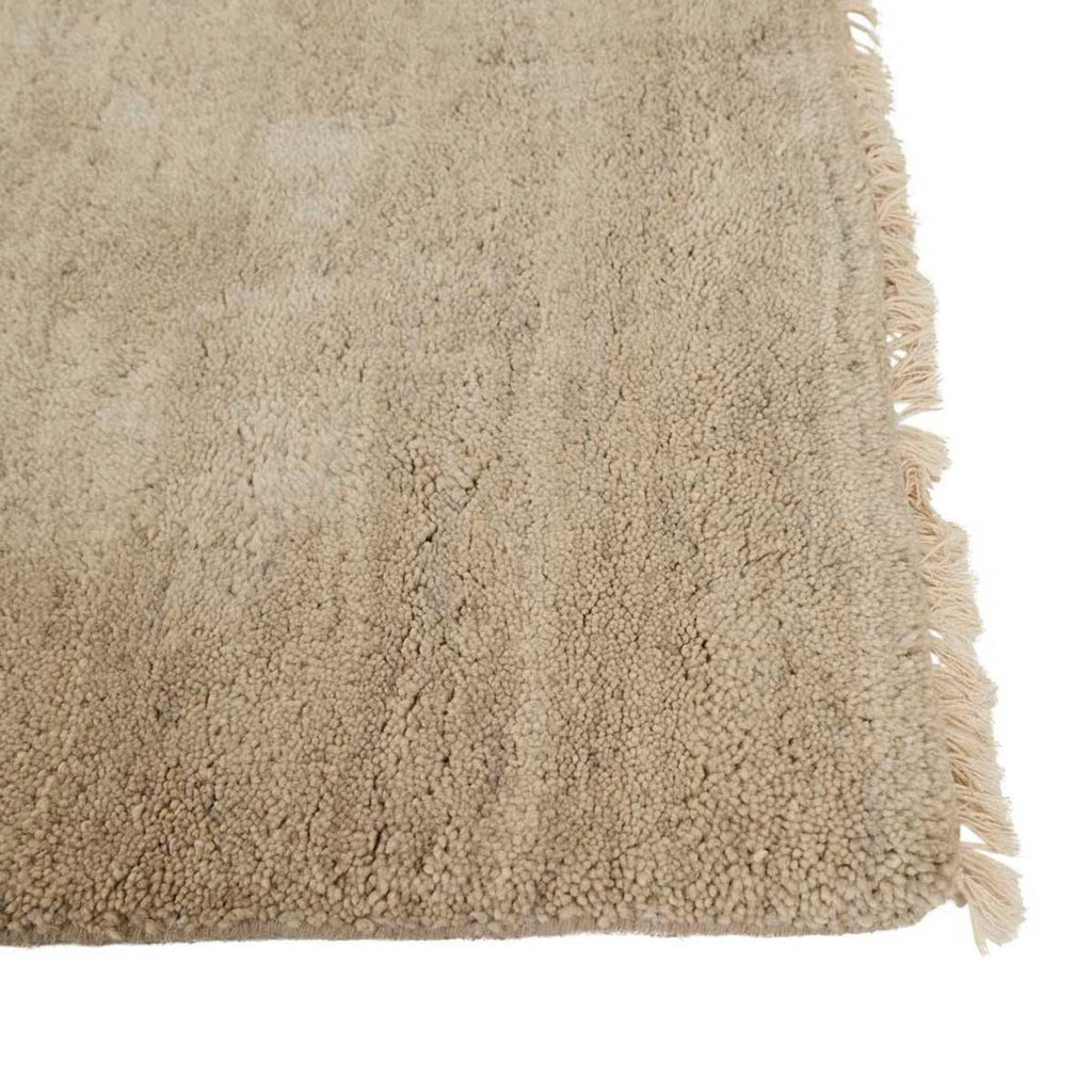  Corner of a soft handloomed rug in a soft beige Pumice colour by Soren Liv. The edges are lightly fringed