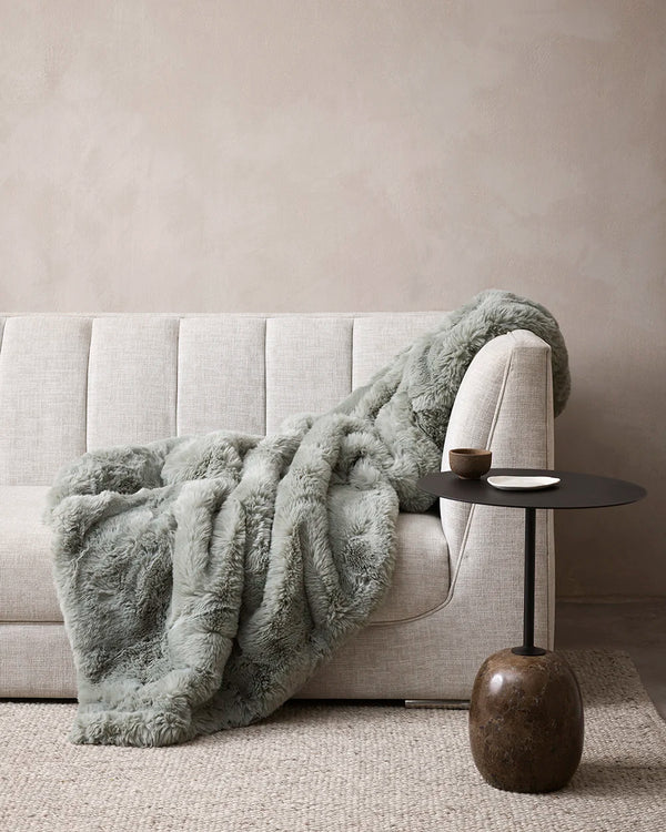 Baya green 'Seafoam' faux fur throw blanket draped over a couch