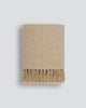 Light brown throw blanket with tasseled fringe, the Baya 'Richmond Putty' seen folded