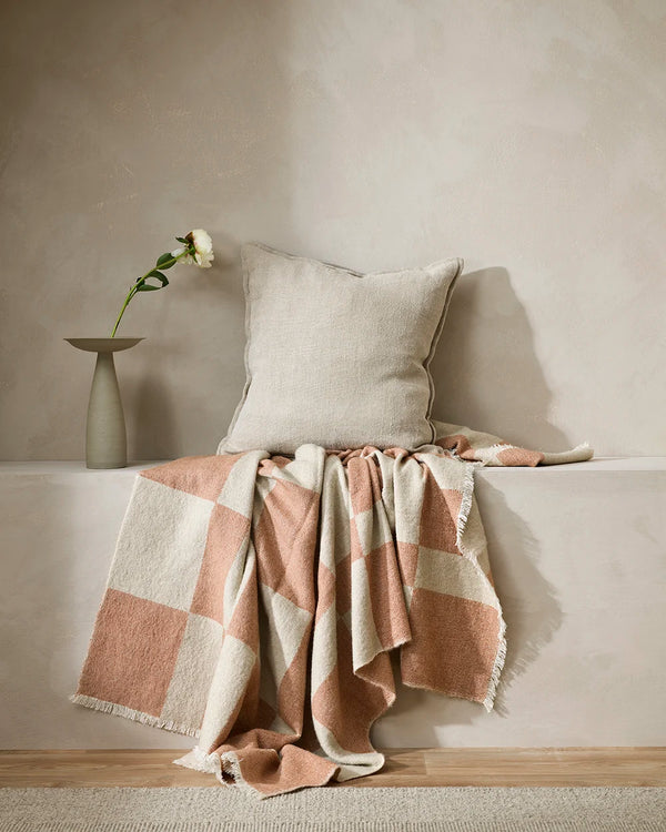 The Baya Winton throw blanket in beige and coral colours, draped in a modern setting