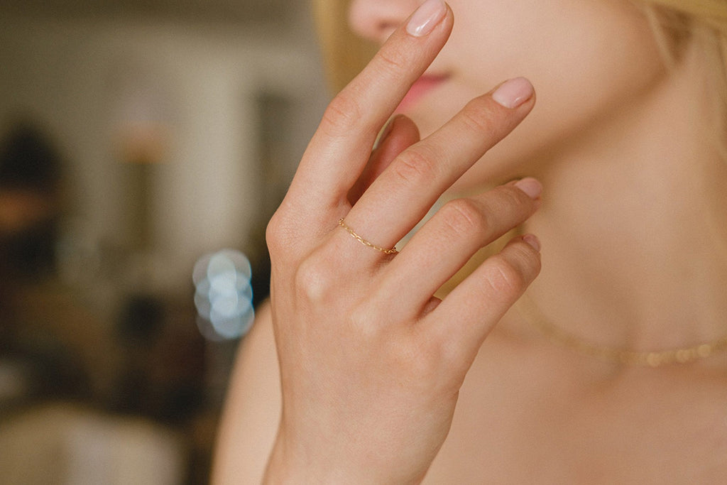 A woman wearing a beautiful, delicate chain ring made with yellow gold-fill by French designers Zoaje
