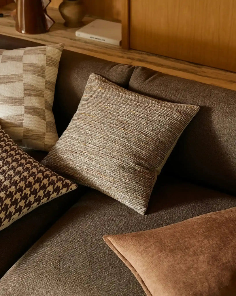 The 'Vista Natural' cushion by Weave Home nz, seen on a brown couch with other designer cushions