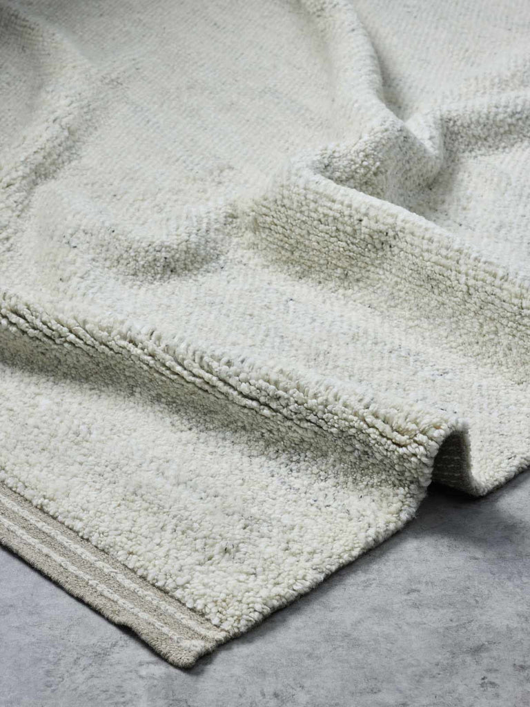 A luxurious, deep-cut pile floor rug in 100% NZ wool made by Tribe Home. A soft beige fawn colour, with the depth of the pile offset by a linear border. 