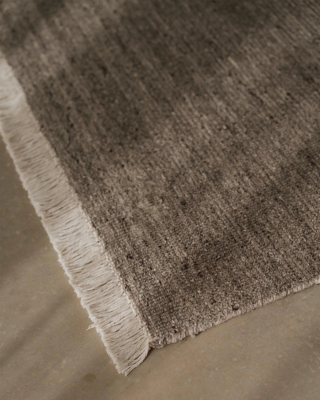 Weave Home Anton wool rug in Ash, close view of the cut and loop pile and cream cotton fringe