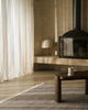 Weave Home Anton wool rug in Ash in a living room with a black fireplace and linen curtains