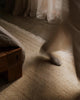 Weave Home Anton wool rug in Sand in a bedroom, with sunlight falling across the pile