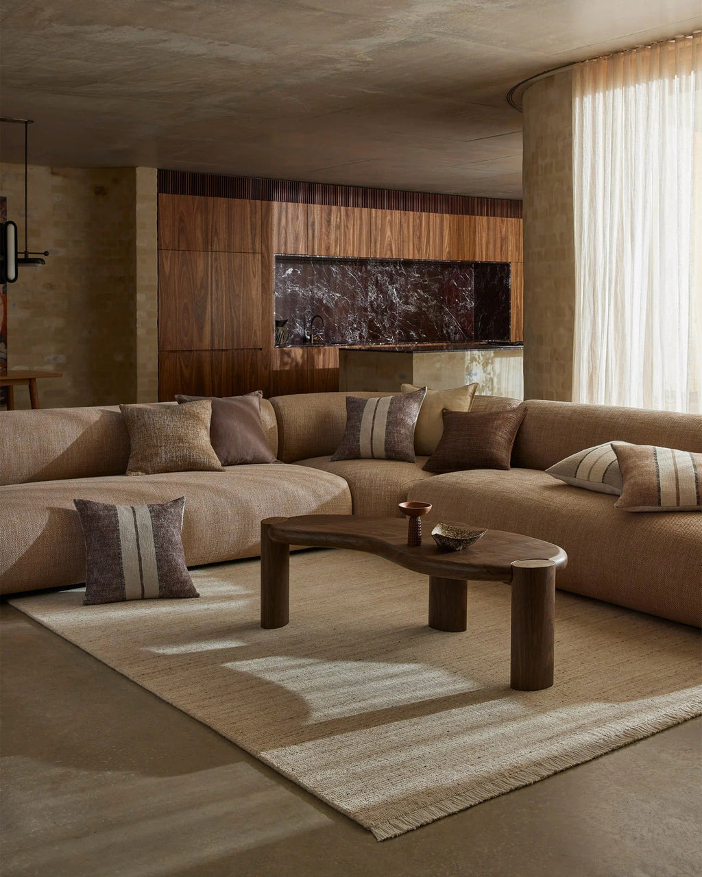 Weave Home Anton wool rug in Sand under a coffee table in a living room with a curved sofa