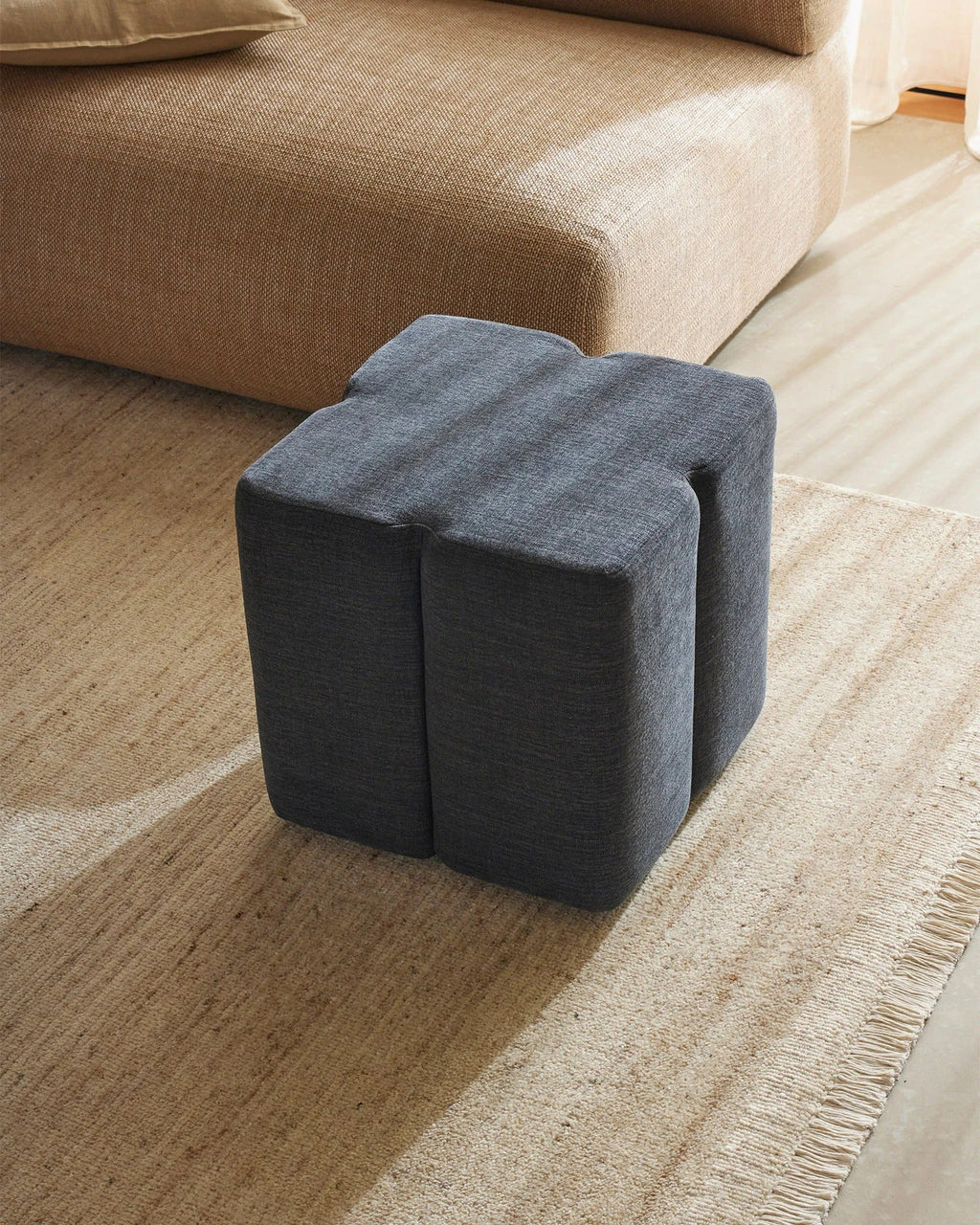 Weave Home Anton wool rug in Sand with a dark blue ottoman beside a tan sofa
