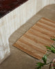 Weave Home Arden Jute Doormat in Natural placed beside a dark marble bench
