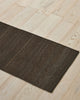 Weave Home Ivano jute doormat in Graphite, angled view on a herringbone wood floor.