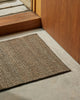 Weave Home Ivano jute doormat in Graphite at a concrete entrance step, close view.