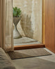 Weave Home Ivano jute doormat in Graphite styled at a timber entranceway.