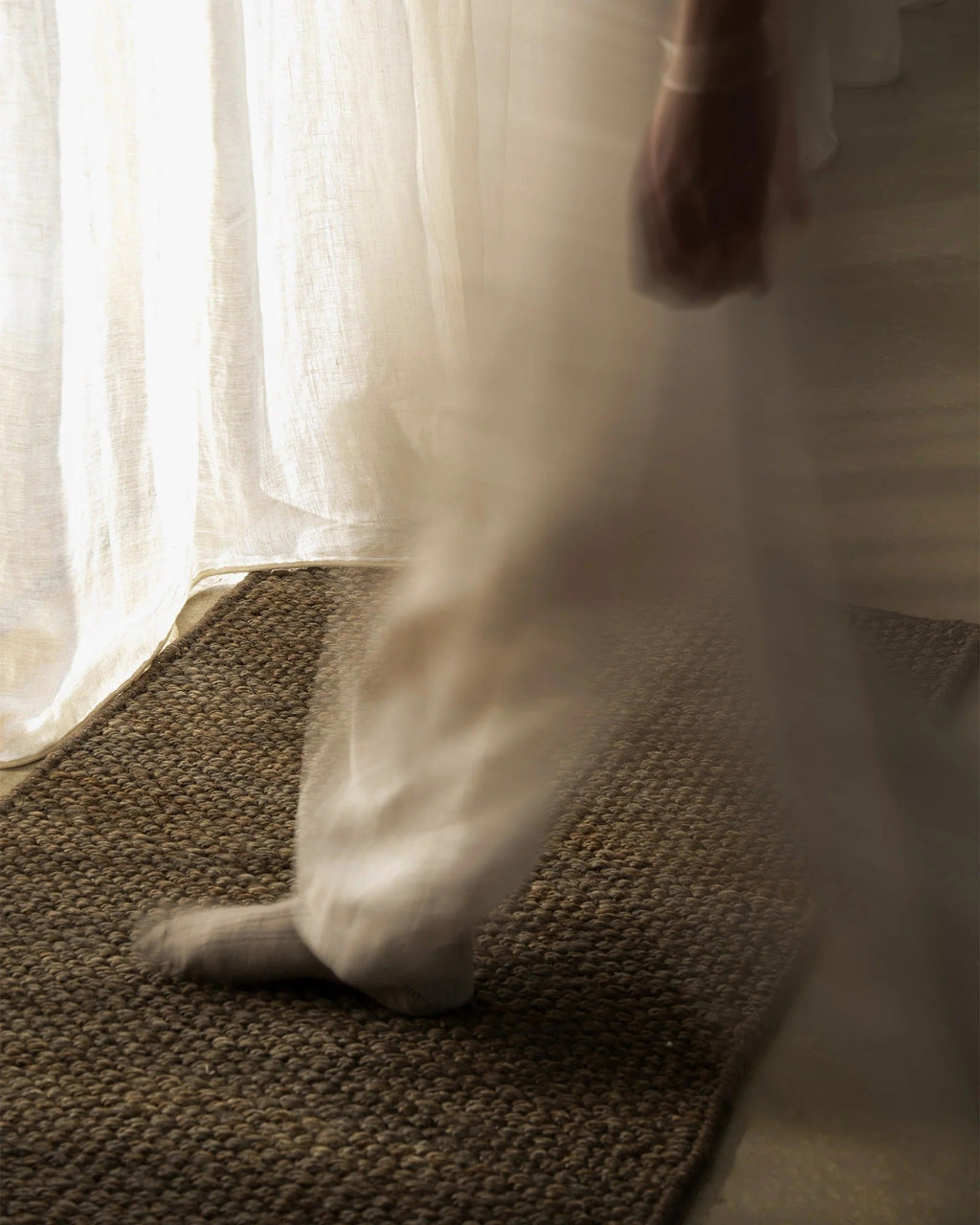 Weave Home Ivano jute doormat in Graphite underfoot near a sunlit sheer curtain.