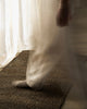 Weave Home Ivano jute doormat in Graphite underfoot near a sunlit sheer curtain.
