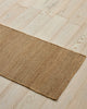 Weave Home Ivano jute doormat in Wheat, angled view on a herringbone wood floor.