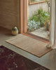 Weave Home Ivano jute doormat in Wheat styled at a timber entranceway.