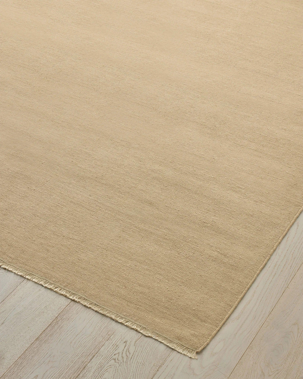 Weave Home Jacqueline wool rug in Barley, close-up of the flatweave texture and fringe on a timber floor.