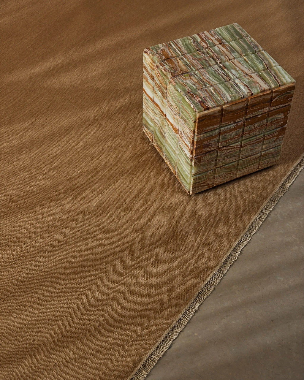 Weave Home Jacqueline wool rug in Brulee, styled with a patterned cube side table showing the fringed edge.