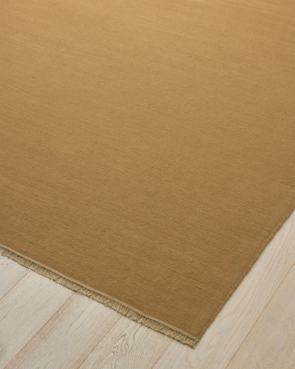 Weave Home Jacqueline wool rug in Brulee, close-up of the flatweave texture and fringe on a timber floor.