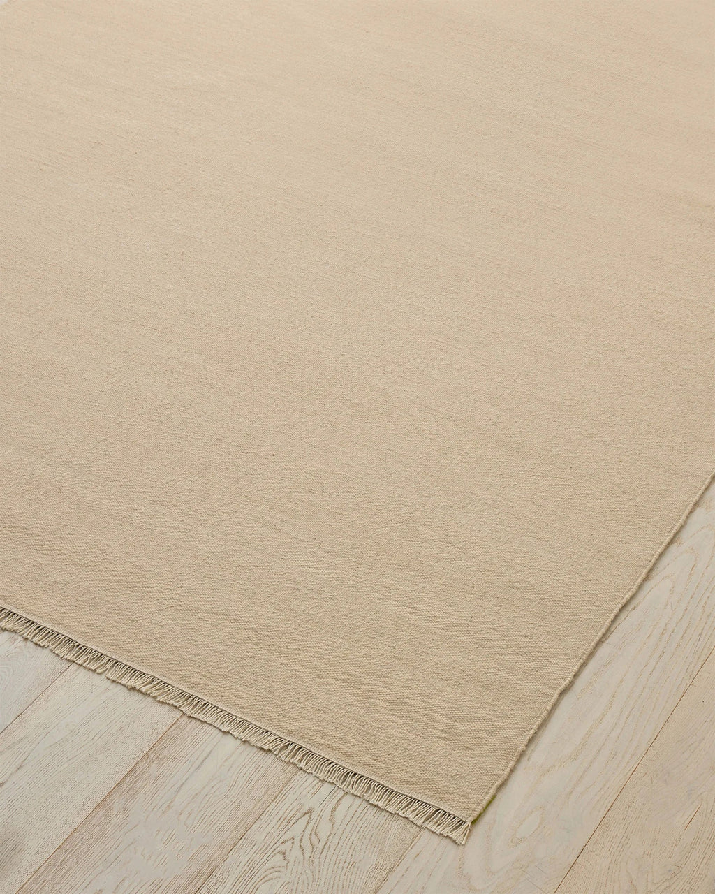 Weave Home Jacqueline wool rug in Cashew on a pale timber floor, showing the fringed corner