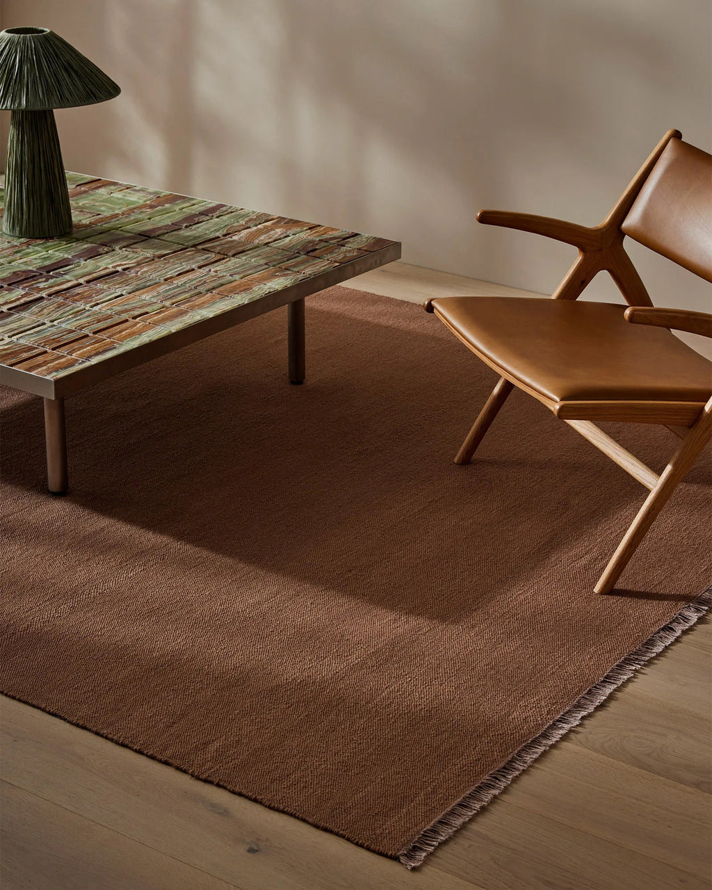 Weave Home Jacqueline wool rug in Rosewood in a living room with a leather lounge chair and low stone table