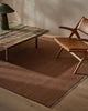 Weave Home Jacqueline wool rug in Rosewood in a living room with a leather lounge chair and low stone table