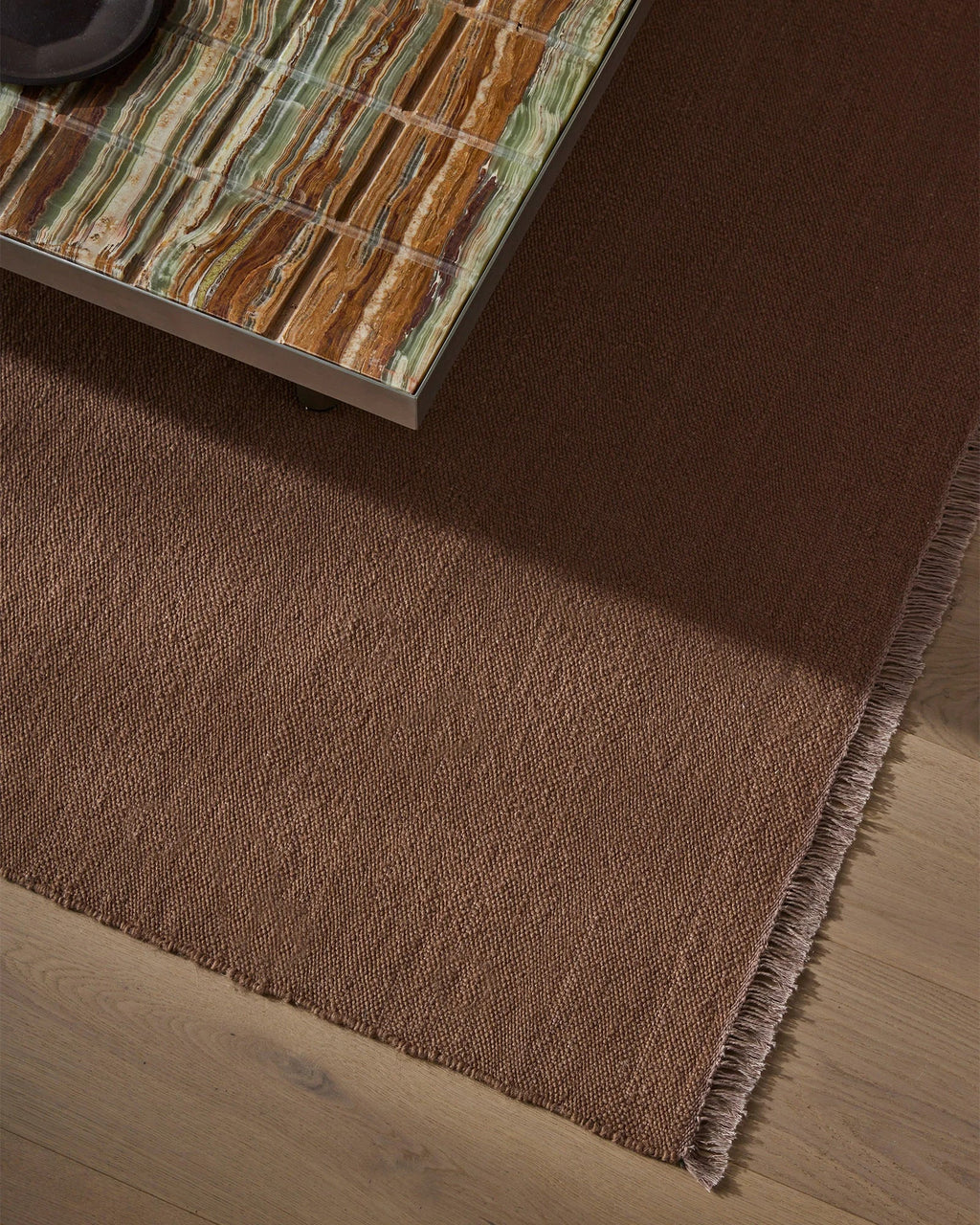 Weave Home Jacqueline wool rug in Rosewood, close view of the flatweave beneath a stone-topped table