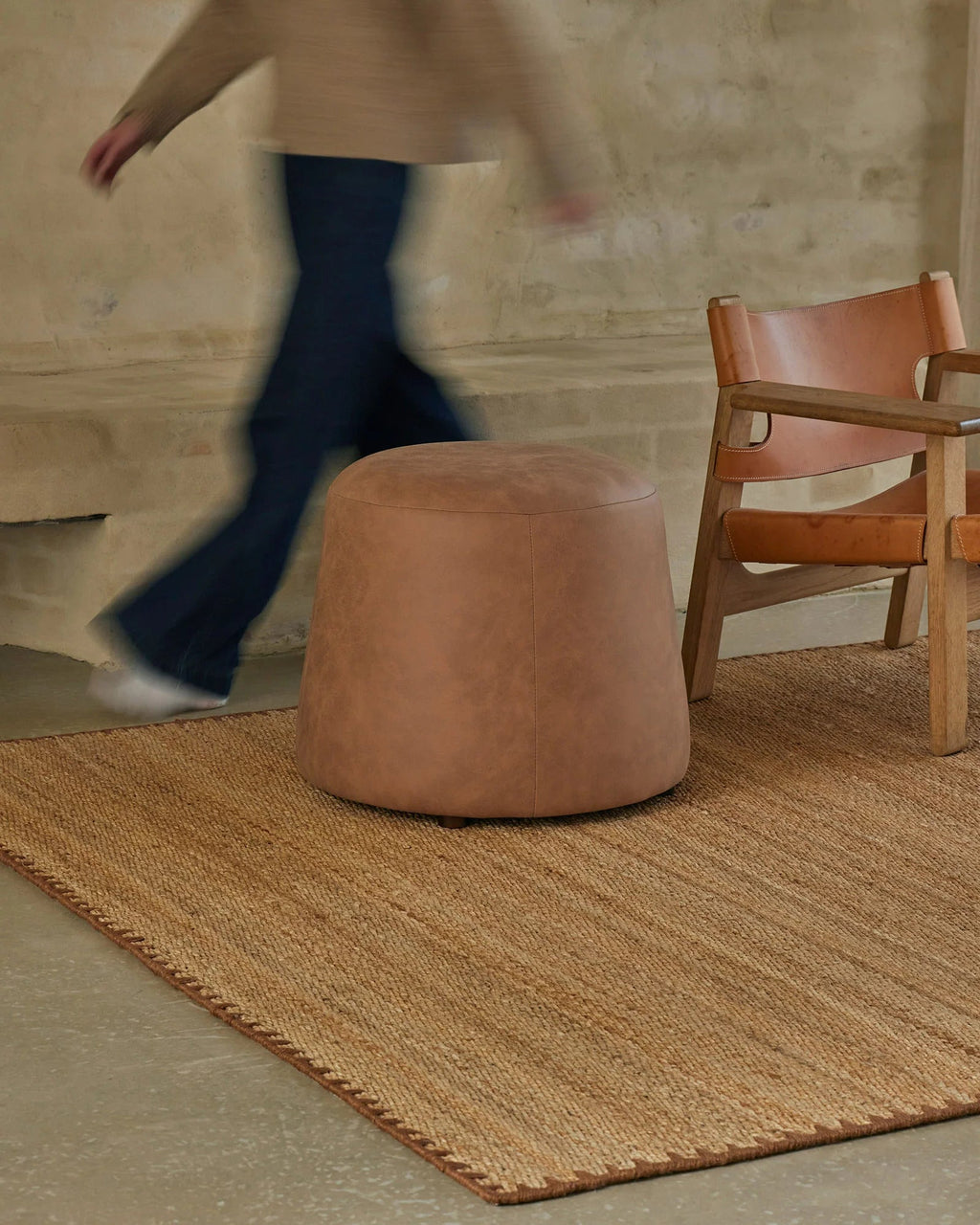 Weave Home Monroe jute rug in Biscuit with a leather pouffe and a leather sling chair