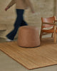 Weave Home Monroe jute rug in Biscuit with a leather pouffe and a leather sling chair