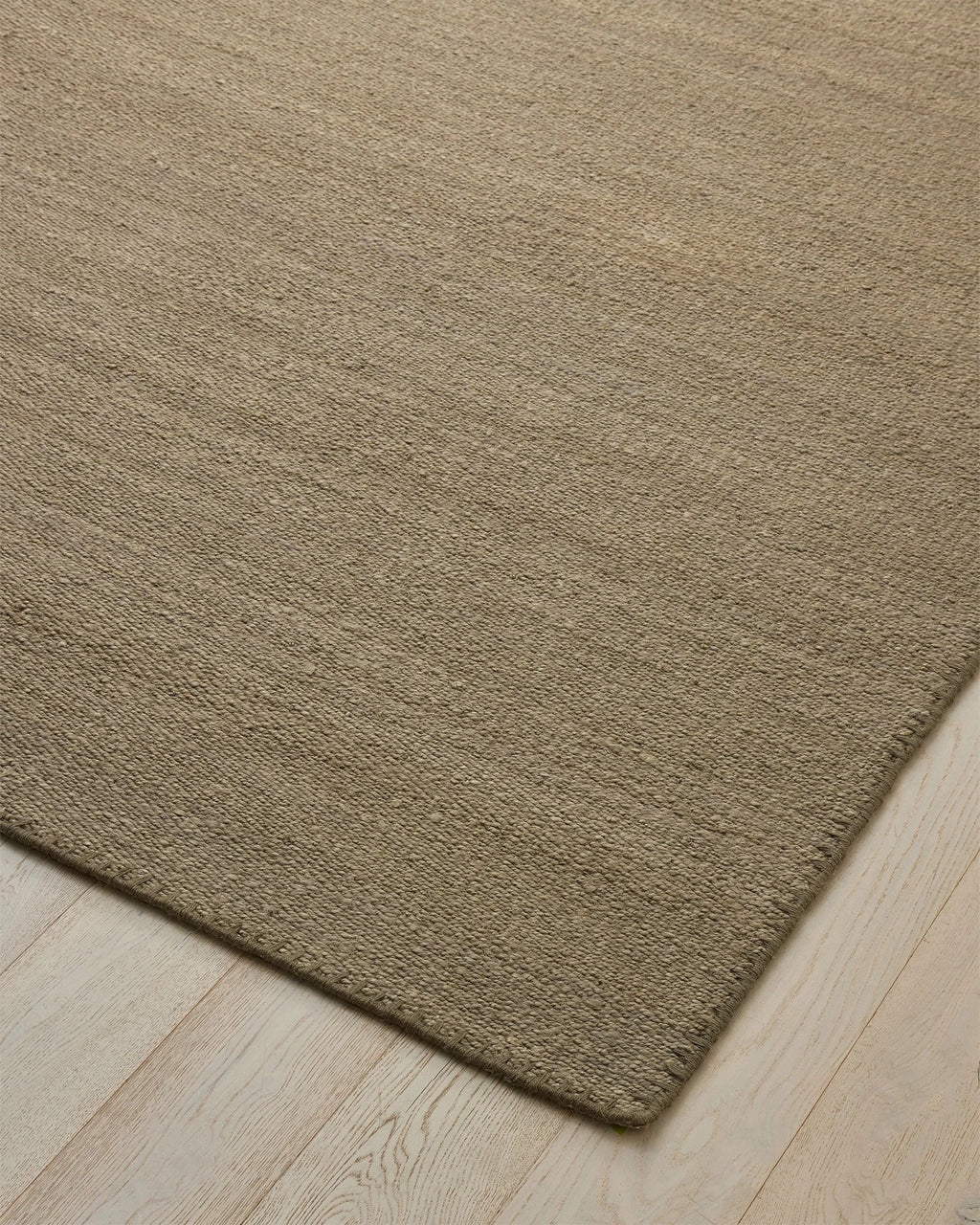 Weave Home Monroe jute rug in Flint on a pale timber floor, showing the stitched border and corner