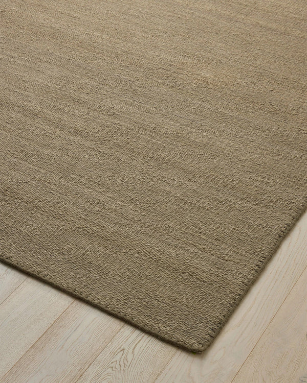 Weave Home Monroe jute rug in Flint on a pale timber floor, showing the stitched border and corner
