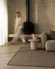 Weave Home Monroe jute rug in Flint beside a fireplace, with a stone side table and a linen sofa