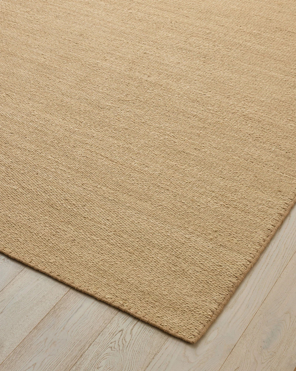 Weave Home Monroe jute rug in Oat on a pale timber floor, showing the stitched border and corner