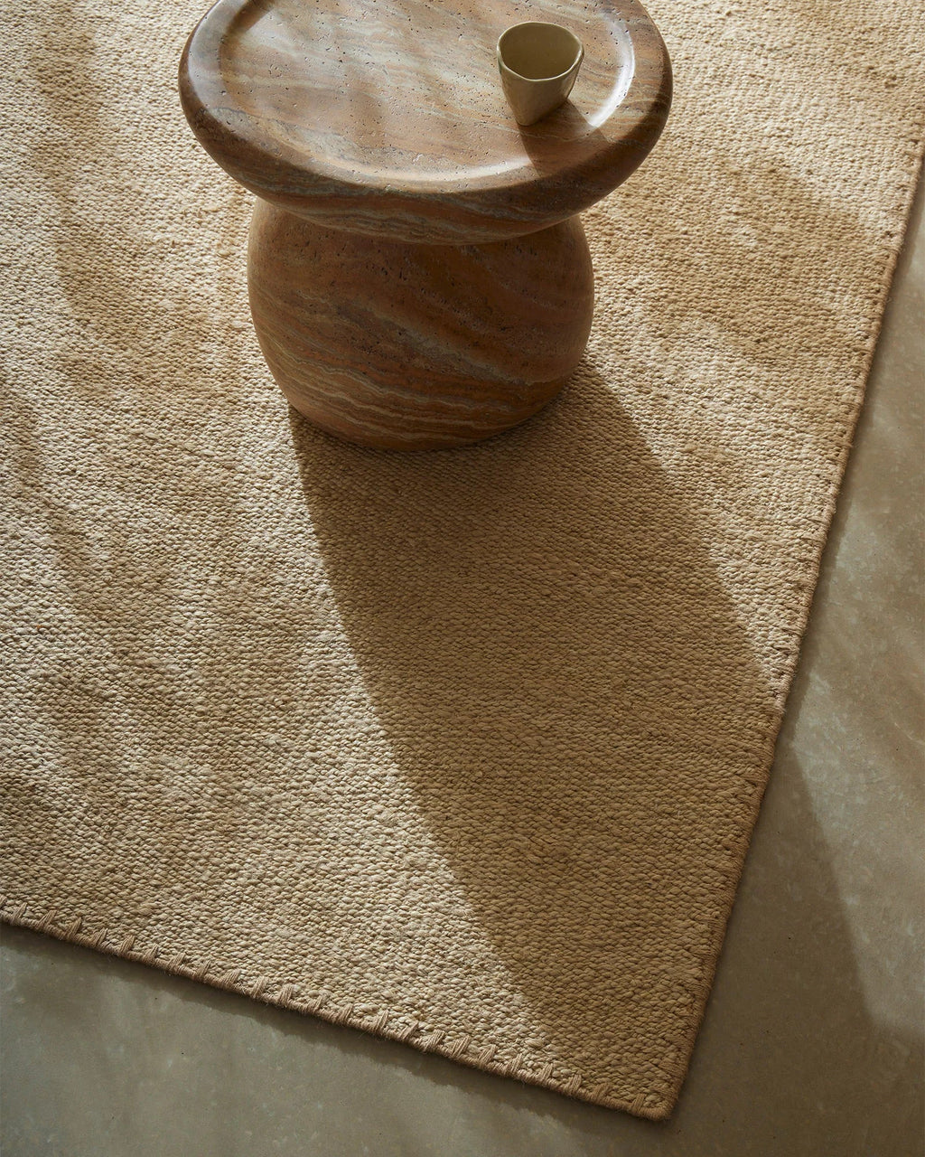 Weave Home Monroe jute rug in Oat, close view of the weave and border beside a stone side table