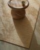 Weave Home Monroe jute rug in Oat, close view of the weave and border beside a stone side table